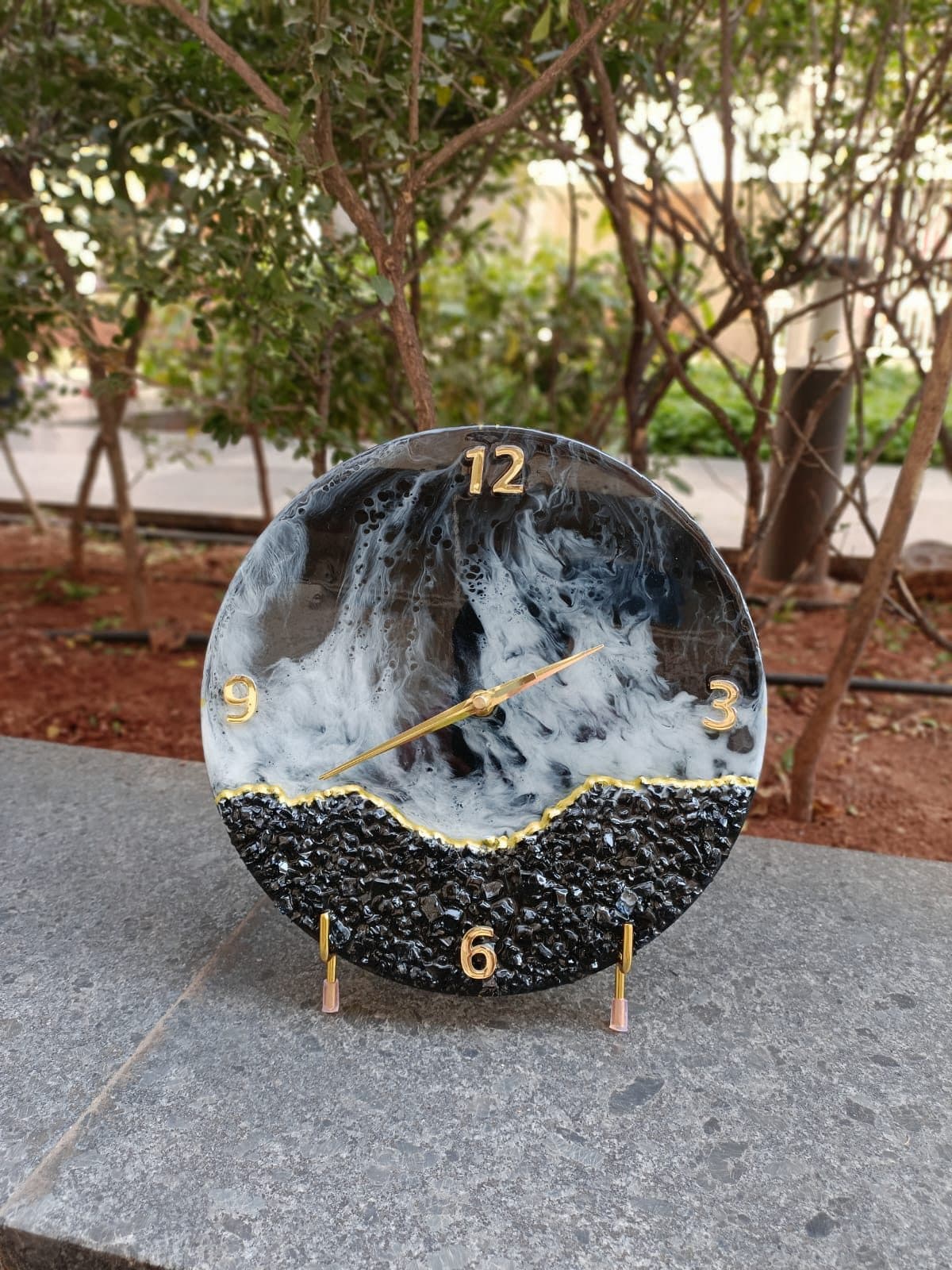 Round resin clock with a black, white and gold ocean-wave edge