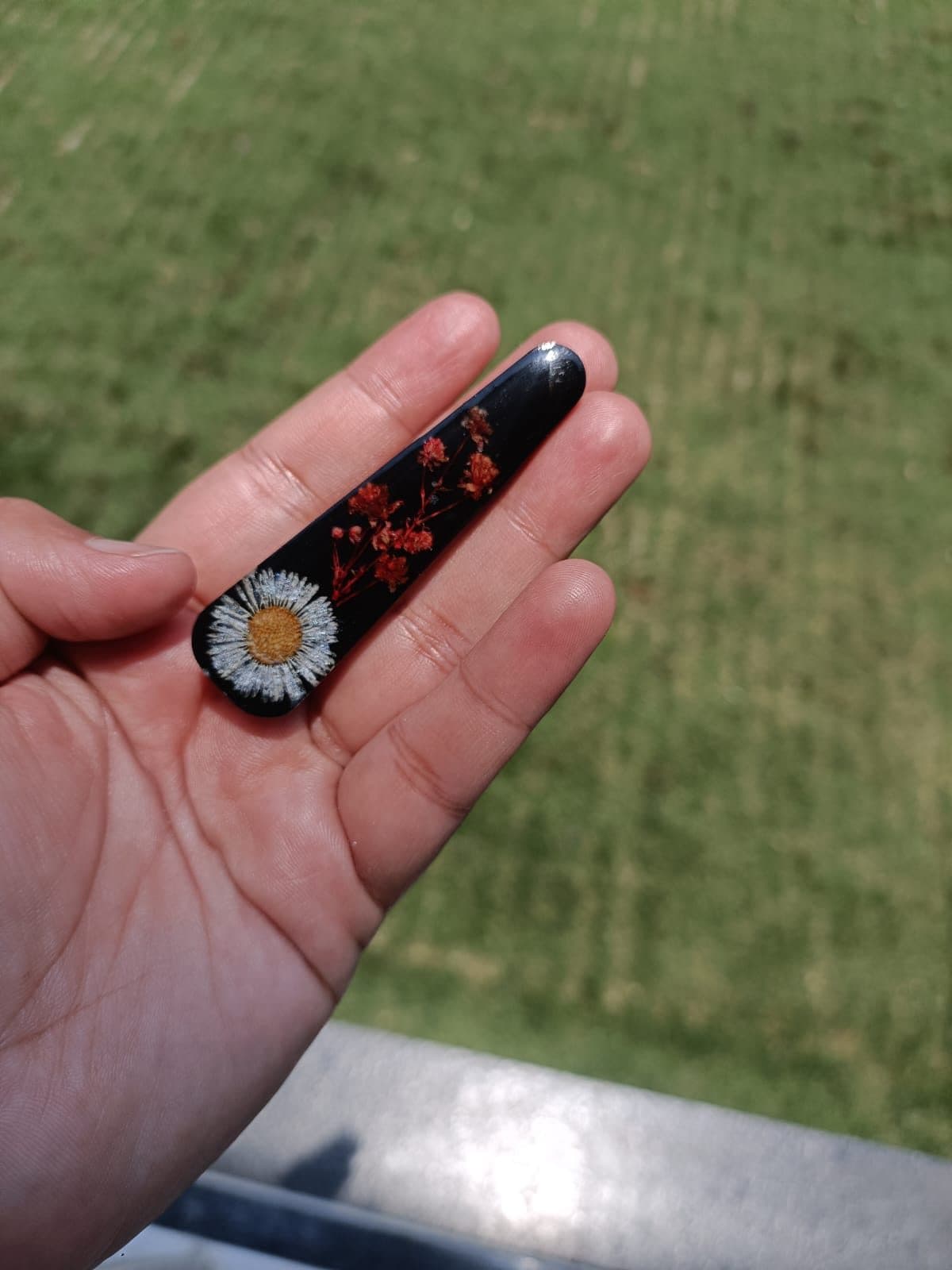 Black hair clip with a white daisy in resin